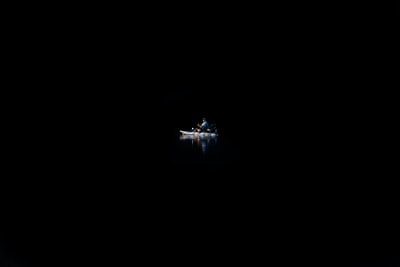 一个人坐在独木舟上，在完全黑暗的水中。